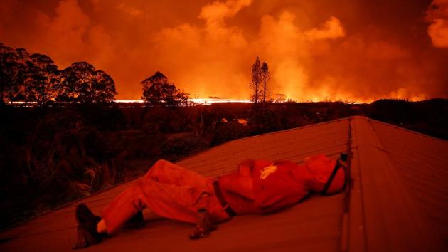 Mark Clawson rests on a neighbour's roof. The sky glows red from lava in the distance. The air, heavy with sulfurous “vog” pollution leaves residents with scratchy throats. Clawson said he had been living his dream in Hawaii. He had built his home from scratch. Revisiting it however, was an “exercise in futility.” (Terray Sylvester / REUTERS) Mark Clawson rests on a neighbour's roof. The sky glows red from lava in the distance. The air, heavy with sulfurous “vog” pollution leaves residents with scratchy throats. Clawson said he had been living his dream in Hawaii. He had built his home from scratch. Revisiting it however, was an “exercise in futility.” (Terray Sylvester / REUTERS)