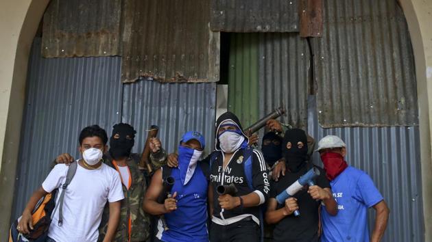 Anti-government protesters pose for a photo with their homemade mortars outside a shopping center with a store covered by metal sheeting to protect it from looting. Protesters use rocks, Molotov cocktails and homemade mortars fashioned from welded pipe segments to confront police who use with tear gas, rubber bullets and, in some cases, live rounds. (Esteban Felix / AP)