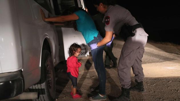 A two-year-old Honduran asylum seeker cries as her mother is searched and detained near the US-Mexico border on June 12, 2018 in McAllen, Texas.(AFP Photo)