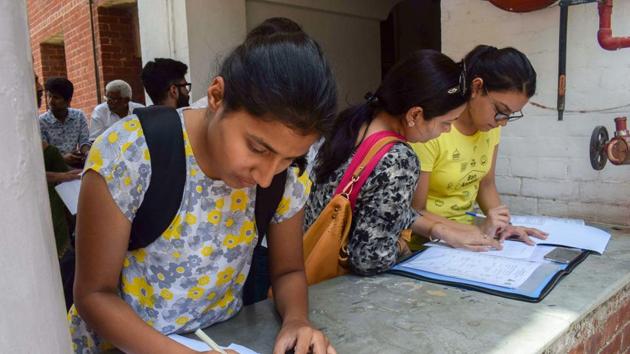 Students fill in application forms at North Campus after the first cut-off list for admissions to the colleges, under Delhi University, were declared in New Delhi on Tuesday, June 19, 2018. The admission under the first cut-off list will end on Thursday at 1pm for regular colleges and 7pm for evening colleges.(PTI)