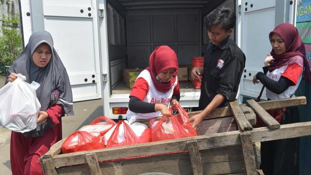 volunteers of the programme A Blessing to Share unload uneaten food from a cart for distribution in a slum area. “There are lots of weddings in Indonesia and lots of extra food,” said programme founder Astrid Paramita. “And there are lots of hungry people unfortunately, so this programme is trying to close that gap between the rich and needy.” (Adek Berry / AFP)