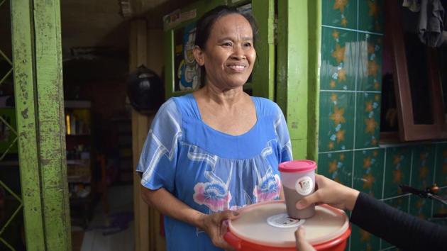 An elderly woman receives food from A Blessing to Share, in a slum area in Jakarta. Since starting in November, about 50 weddings have participated in the programme with about 1.6 tons of food collected for distribution through a local food bank. (Adek Berry / AFP)