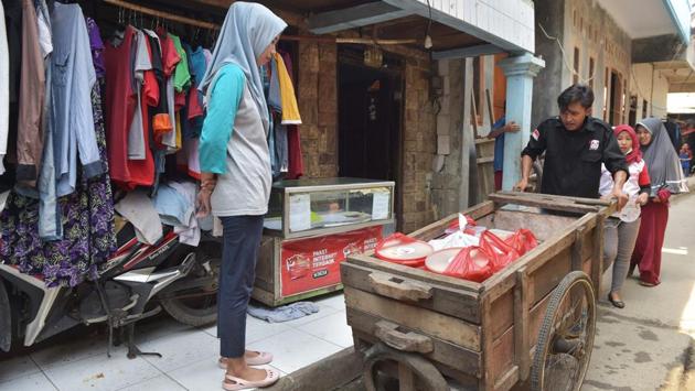 A volunteer of the programme wheels a trolley distributing uneaten food in a Jakarta slum. So far the programme is fairly limited, but Parmita has big plans and hopes to expand to other cities and also start sourcing edibles from company meetings and conferences. (Adek Berry / AFP)