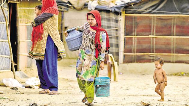 Rohingya woman walk to their tents after fetching drinking water at Chandeni Rohingya camp in Haryana’s Nuh District, in Gurugram.(Parveen Kumar/HT File Photo)