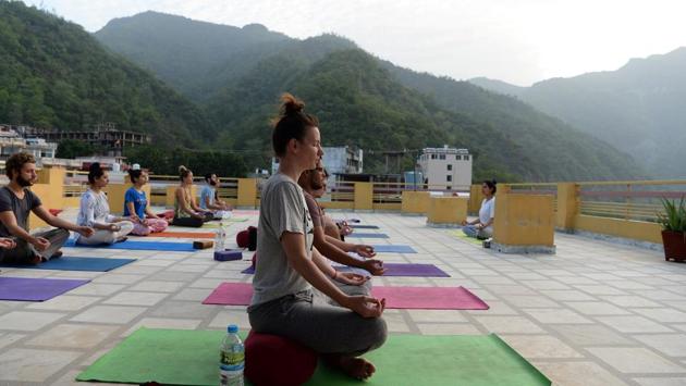 People practice yoga on a terrace at the Anand Prakash yoga ashram in Rishikesh, Uttarakhand. The town, in the foothills of the Himalayas 250 kilometres north of Delhi, is the world centre of yoga, drawing tens of thousands of foreign tourists every year to its dozens of ashram retreats and yoga schools. (Sajjad Hussain / AFP)