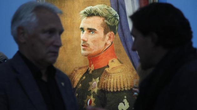 Visitors speak in front of portrait of France's football star Antoine Griezmann’s portrait. (AP)