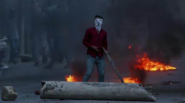 A masked protester watches from a distance as policemen fire tear gas shells towards him during a protest in Srinagar, Jammu and Kashmir on June 21, 2018. (Dar Yasin / AP) A masked protester watches from a distance as policemen fire tear gas shells towards him during a protest in Srinagar, Jammu and Kashmir on June 21, 2018. (Dar Yasin / AP)