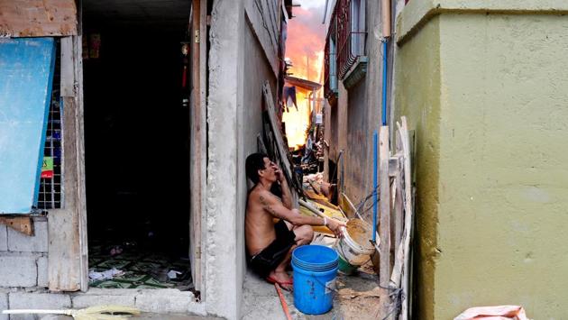A man sits in a narrow alley as his house burns in Muntinlupa, Metro Manila. In a country with a yawning wealth gap, the hardest hit are the hundreds of thousands of urban poor who call the shanties home. (Erik De Castro / REUTERS) A man sits in a narrow alley as his house burns in Muntinlupa, Metro Manila. In a country with a yawning wealth gap, the hardest hit are the hundreds of thousands of urban poor who call the shanties home. (Erik De Castro / REUTERS)