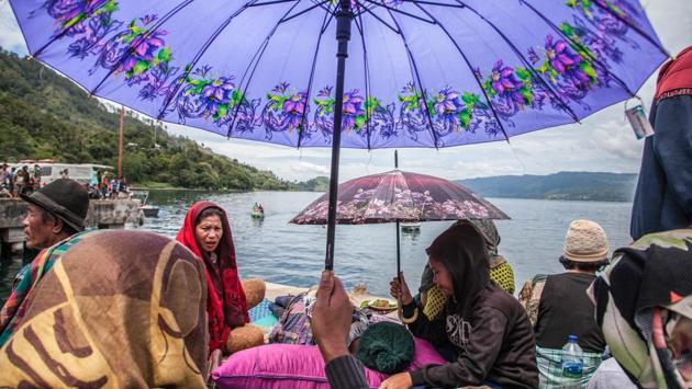 Family members sit together as they wait for rescue teams searching for missing passengers of a ferry that sank into a volcanic lake, at the Lake Toba ferry port in the province of North Sumatra, Indonesia. (Ivan Damanik / AFP)