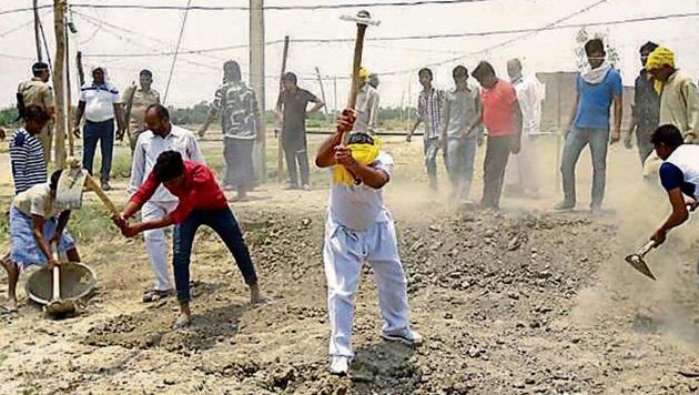 Minister Om Prakash Rajbhar (in yellow turban, centre) at work rebuilding the road leading to his house in Fatehpur Khonda village.(HT Photo)