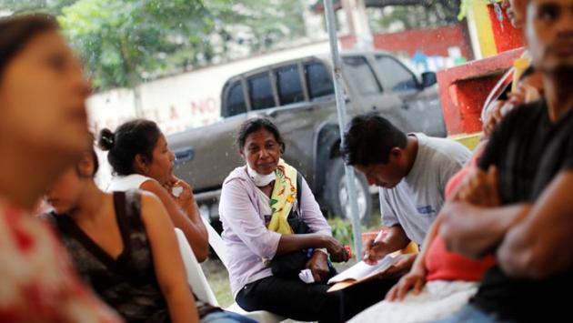 Garcia sits with other residents outside the morgue in Escuintla. An alarm sounds which warns of hot ash, lava fragments, and gases exploding from the volcano and rolling down the mountain, swallowing everything in its path. These alarms suspend the search for more bodies and that is when she returns to the morgue or checks the hospitals. The same routine is continued every day. (Carlos Jasso / REUTERS)