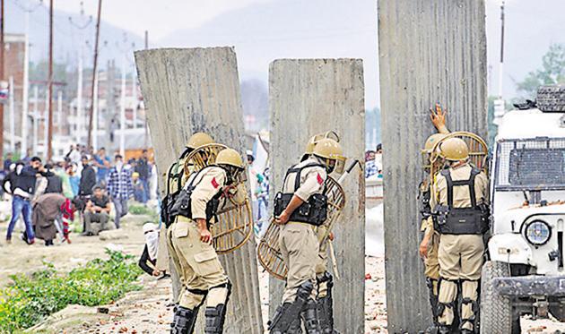 Police take guard behind a barricade as Kashmiri protesters clash with police on the outskirts of Srinagar after forces killed four militants at Nowshera village in South Kashmir on June 22, 2018(Hindustan Times)