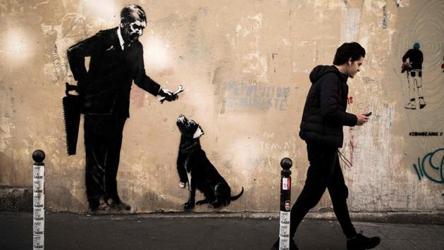 Other murals leave the viewer musing on greed or cruelty: In one a man in a suit is offering a one-legged dog a bone, while a handsaw behind his back raises the possibility that it is the dog’s own leg. (Philippe Lopez / AFP)