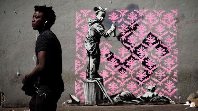 The works are believed to have started to appear as early as last Wednesday, UN-designated World Refugee Day, and some have already been vandalised. This mural, on a street in northern Paris where migrants sleep rough, shows a black girl spraying a pink wallpaper pattern over a swastika. (Philippe Lopez / AFP)