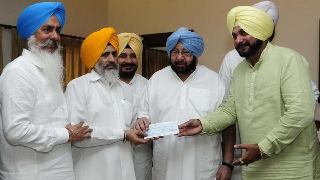 Punjab chief minister Capt Amarinder Singh handing over a cheque to one of the detainees lodged in the Jodhpur jail after Operation Bluestar in Chandigarh on Thursday.(Keshav Singh/HT)