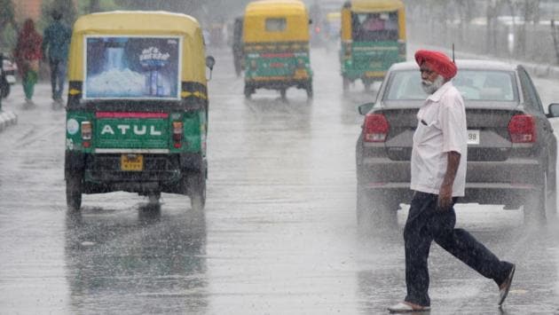 A man crosses the road as it rains in Ludhiana. (Gurminder Singh/HT)
