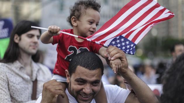 Saad Almontaser, 1, of Brooklyn, waves an American flag over his father Ali, from Yemen, as protesters hold a rally outside of Manhattan Federal Court in New York City. (Byron Smith / Getty Images / AFP)