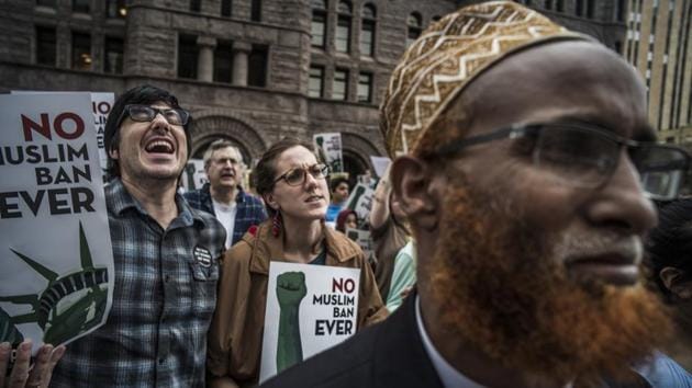 Dave Smallen (L) and his fiancee Caitlin Mahoney (C), who started at the Federal Courthouse attend a rally to oppose the Supreme Court's decision in Minneapolis. Somali Abuturab Hashi stands to the front right. Muslim individuals and groups, as well as other religious and civil rights organizations, expressed outrage and disappointment as the policy claimed discriminated against Muslims and exceeded the president's authority. (Richard Tsong-Taatarii / Star Tribune via AP)