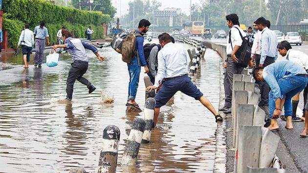 People wade through waterlogged street, near Hero Honda Chowk after heavy rains in Gurugram(Yogendra Kumar/HT Photo)