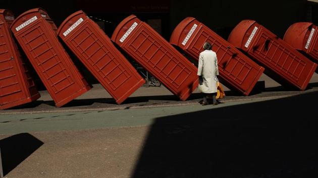 A lady stops to look at ‘Out of Order’ a 1989 red phone box sculpture by British artist David Mach in Kingston upon Thames, south west London, England. (Matt Dunham / AP) 