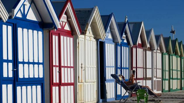 A woman reads a book in front a beach cabin on the pebbled beach in Cayeux-sur-Mer, on the North coast as sunny weather arrives in France. (Pascal Rossignol / REUTERS) 