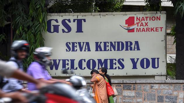 A motorist rides past a GST Seva Kendra board outside the Central tax building, in Bengaluru on Thursday.(PTI Photo)