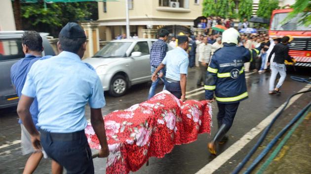 Indian Air Force personnel and a Mumbai Fire personnel carry the body of one of the victims from the site of the chartered plane crash, in Ghatkopar in Mumbai.(PTI Photo)