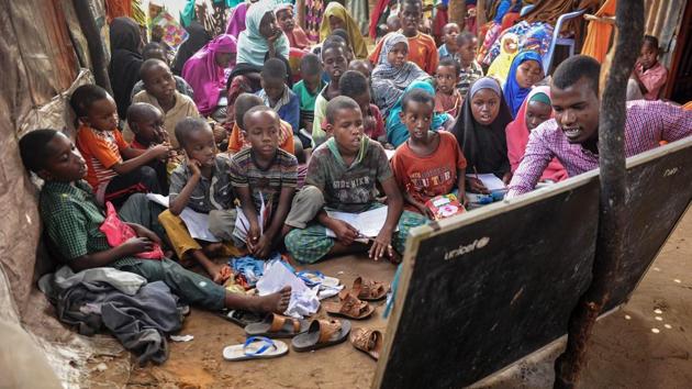 University student Yahye Mohamed (R) teaches alphabets and numbers to displaced Somali children and teenagers as a volunteer teacher at a makeshift school at the Badbado IDP camp in Mogadishu, Somalia. (Mohamed Abdiwahab / AFP) 