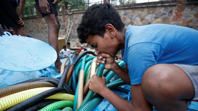 A boy uses his mouth to pump water out from a municipal tanker to fill his containers. In Sangam Vihar, another Delhi district, home to about 1.5 million residents, private water tankers which come to the area once in a while charge a hefty price, the suppliers citing the cragged and unmetalled road that connects Sangam Vihar to the city. (Adnan Abidi / REUTERS)
