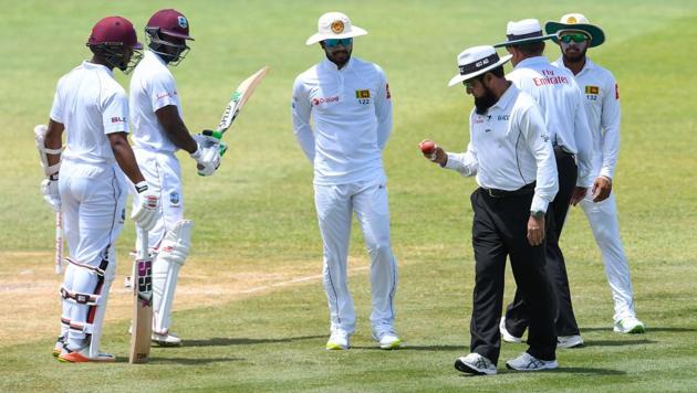 Dinesh Chandimal (C) of Sri Lanka looks at the ball in umpire Aleem Dar's hand while Shai Hope (L) and Devon Smith (2L) of West Indies watch during day 3 of the 2nd Test between West Indies and Sri Lanka at Daren Sammy Cricket Ground, Gros Islet, St. Lucia, on June 16, 2018.(AFP)