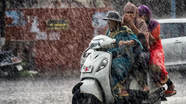 Commuters make their way across a street during heavy rain, in Ahmedabad on July 2.(PTI Photo)