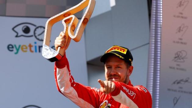 Ferrari's Sebastian Vettel celebrates with his trophy on the podium after finishing third.(REUTERS)