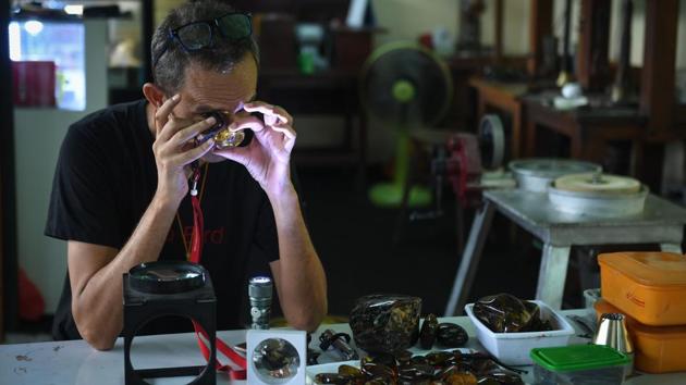 Akbar Khan, a 52-year-old self-described 'extreme fossil in amber hunter' inspects Kachin amber at his streetside stall in Bangkok. Amateur amber hunters aside, the main challenge for traders and collectors is working in a conflict zone. An upsurge in fighting between the army and the Kachin Independence Army (KIA) over recent years has left more than 100,000 people displaced in the region. (Lilian Suwarnarumpha / AFP) 