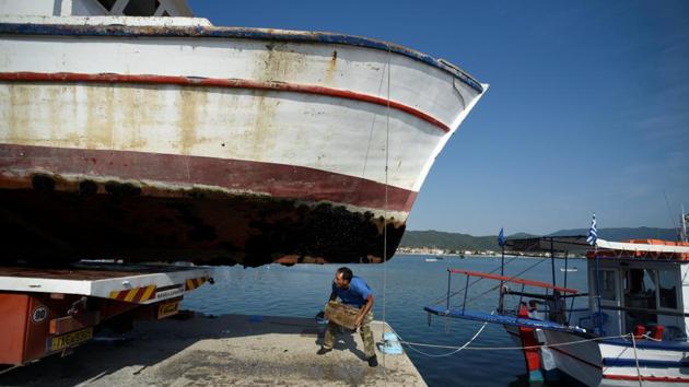 A worker kneels under ‘Panagiotis’ before it is sent for destruction. Payments range from 6,000 to 260,000 euros depending on the size of the boat. People can simply turn in their licences and find something else to do with their vessel. But to get the full payment, they have to take their boat to the scrap yard. (Alexandros Avramidis / REUTERS)