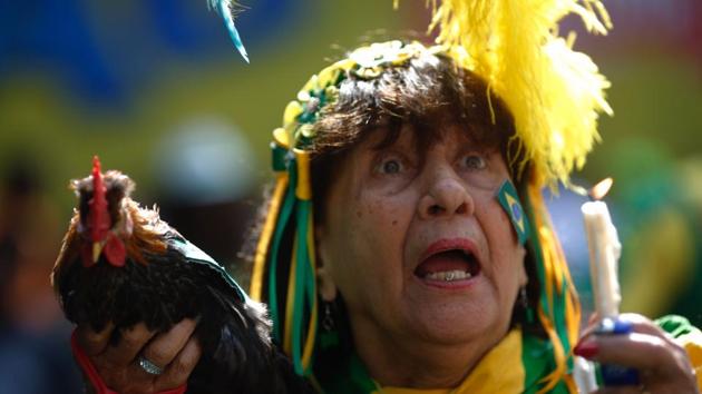 A fan of Brazil holds a hen as she watches the World Cup match between Brazil and Mexico on a big screen in Rio de Janeiro. (AFP) 