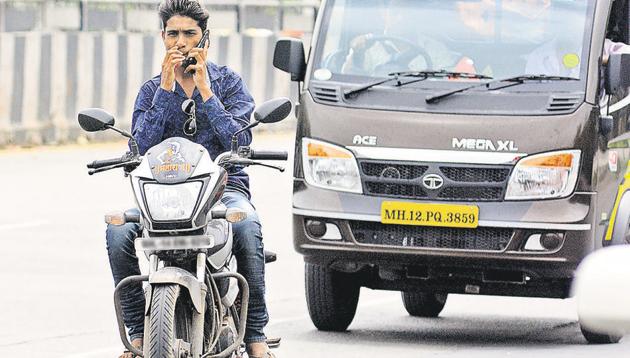 A motorist speaks on a mobile phone while riding a bike at Ahmednagar road on Monday.(SHANKAR NARAYAN/ HT PHOTO)