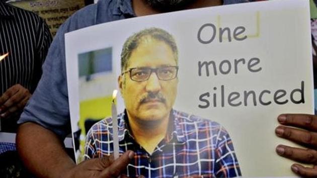 A journalist participates in a silent protest against the brutal killing of a senior Kashmiri journalist Shujaat Bukhari, portrait seen, in Kolkata on June 15, 2018.(AP)
