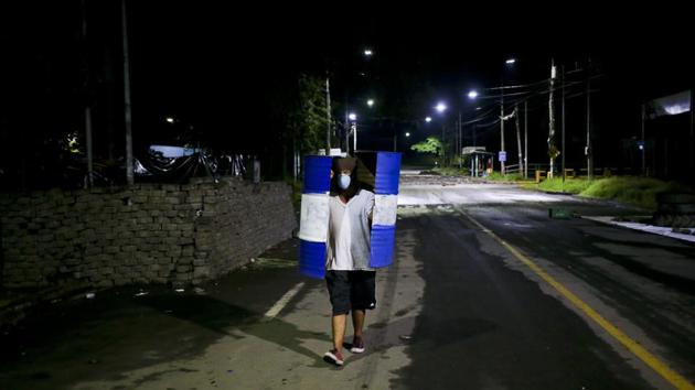 A student walks outside the school carrying a metal trash barrel, cut in half and used as a shield. An ambulance arrived, but students sent it away because they did not trust that he would receive care at a public hospital and feared it might carry attackers. Students took Chavarria to a private hospital where he later died. (Esteban Felix / AP)