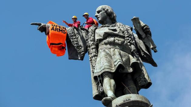Activists from the Spanish Proactiva Open Arms charity place a life jacket on the Christopher Columbus statue after the Open Arms rescue boat arrived at a port in Barcelona, Spain, carrying migrants rescued off Libya. (Albert Gea / REUTERS)