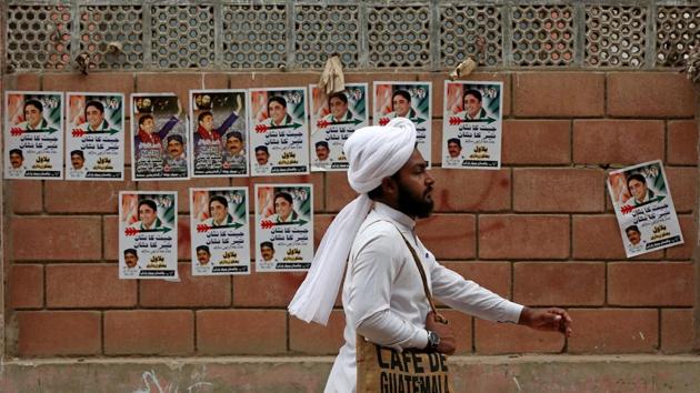 A man wearing a turban walks past a wall with electoral campaign posters ahead of general elections in Karachi, Pakistan on July 5.(REUTERS)