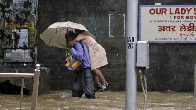 A man carries a child past a waterlogged street in Mumbai on July 3, 2018. (Rajanish Kakade / AP)