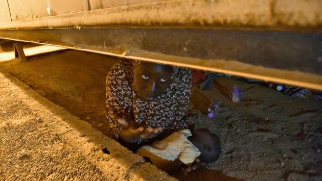 A Nigerien migrant hides with her newborn child under a structure as she tries to avoid deportation at a transit centre for migrants in Tamanrasset in southern Algeria. (Ryad Kramdi / AFP)