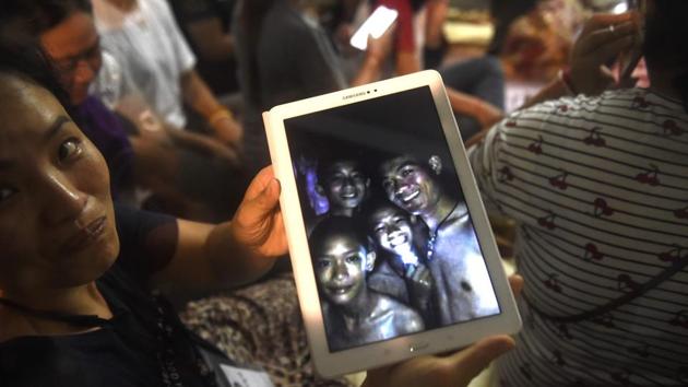 A family member shows a picture of four of the twelve missing boys near the Tham Luang cave at the Khun Nam Nang Non Forest Park in Mae Sai. (Lillian Suwanrumpha / AFP)