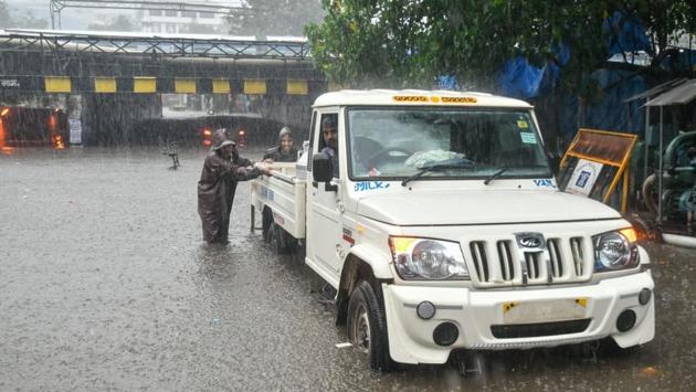 People were seen wading through knee-deep water as a car was washed away in Andheri. (Sanket S Kashyap/HT Photo)
