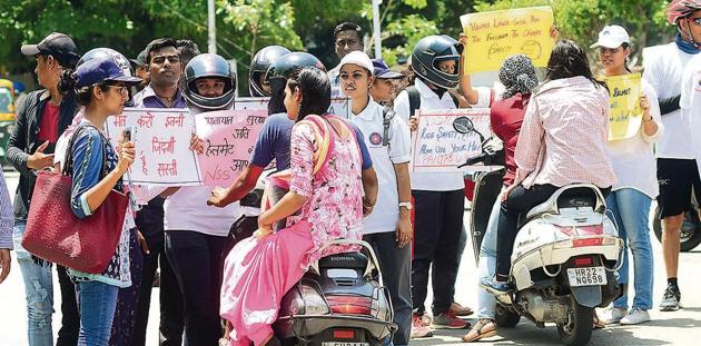 National Service Scheme volunteers raising awareness about the importance of wearing helmets among two-wheeler riders at Panjab University in Chandigarh on Saturday. The UT has made helmets mandatory for all women, except turbaned Sikh women.(Ravi Kumar/HT)