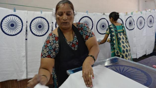 Nirmala S. Ilkal (L) prepares to screen print the central strip of the Indian national flag. “The piece is rejected if there is even the slightest error,” Ilakal, who has worked in the printing department for 15 years, said. (Manjunath Kiran / AFP)