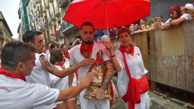 Participants touch a San Fermin effigy before running next to Jose Escolar fighting bulls on the second day of the festival. (Ander Gillenea / AFP) Participants touch a San Fermin effigy before running next to Jose Escolar fighting bulls on the second day of the festival. (Ander Gillenea / AFP)