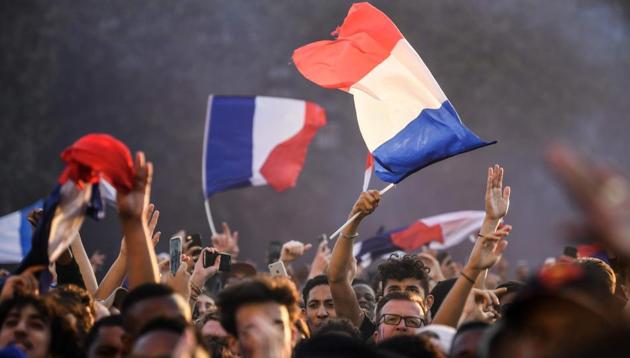 People cheer and wave French flags as they gather at a fan zone in Paris during their FIFA World Cup 2018 match against Belgium.(AFP)