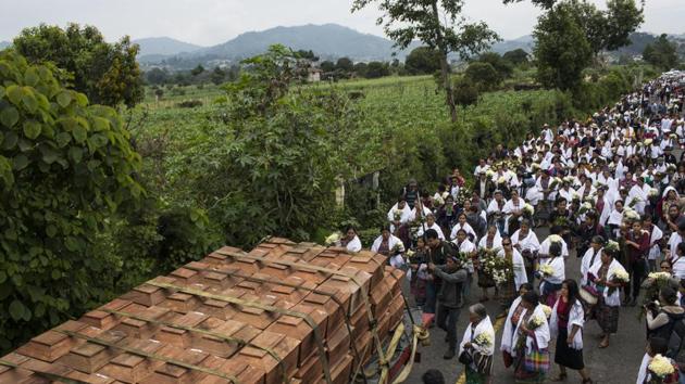 Villagers walk behind coffins. Women from the village of San Juan Comalapa, 80 kilometers west of Guatemala City, spent years saving money and raising donations to buy a plot of land where an army camp once stood. During the 1960-1996 conflict, people from across the country were abducted and brought here by soldiers, then were tortured, killed and buried in mass graves. (Rodrigo Abd / AP) Villagers walk behind coffins. Women from the village of San Juan Comalapa, 80 kilometers west of Guatemala City, spent years saving money and raising donations to buy a plot of land where an army camp once stood. During the 1960-1996 conflict, people from across the country were abducted and brought here by soldiers, then were tortured, killed and buried in mass graves. (Rodrigo Abd / AP)