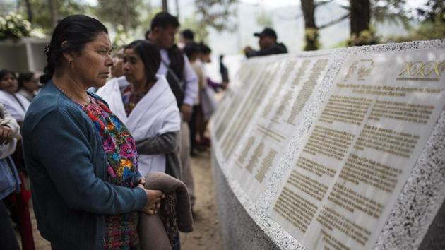 A woman reads the names of people who disappeared during the civil war, at the site where a military camp once operated. The previous night, in the center of town, women had put grass and flower petals on the cement floor of a community center as they blessed the coffins with prayers and incense. (Rodrigo Abd / AP) A woman reads the names of people who disappeared during the civil war, at the site where a military camp once operated. The previous night, in the center of town, women had put grass and flower petals on the cement floor of a community center as they blessed the coffins with prayers and incense. (Rodrigo Abd / AP)